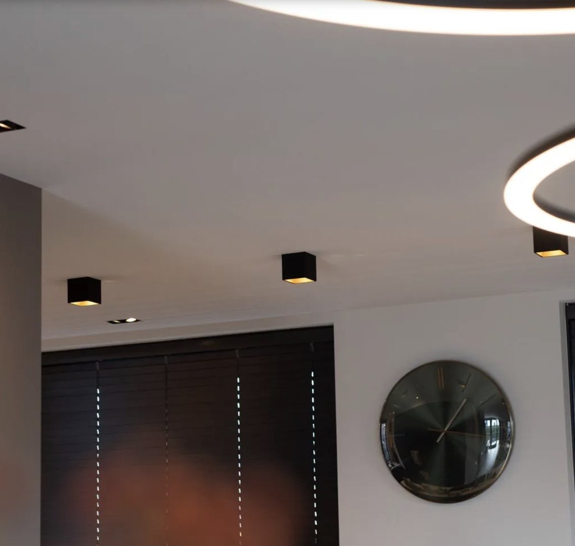 Zwarte opbouwspots en een ringlamp aan het plafond